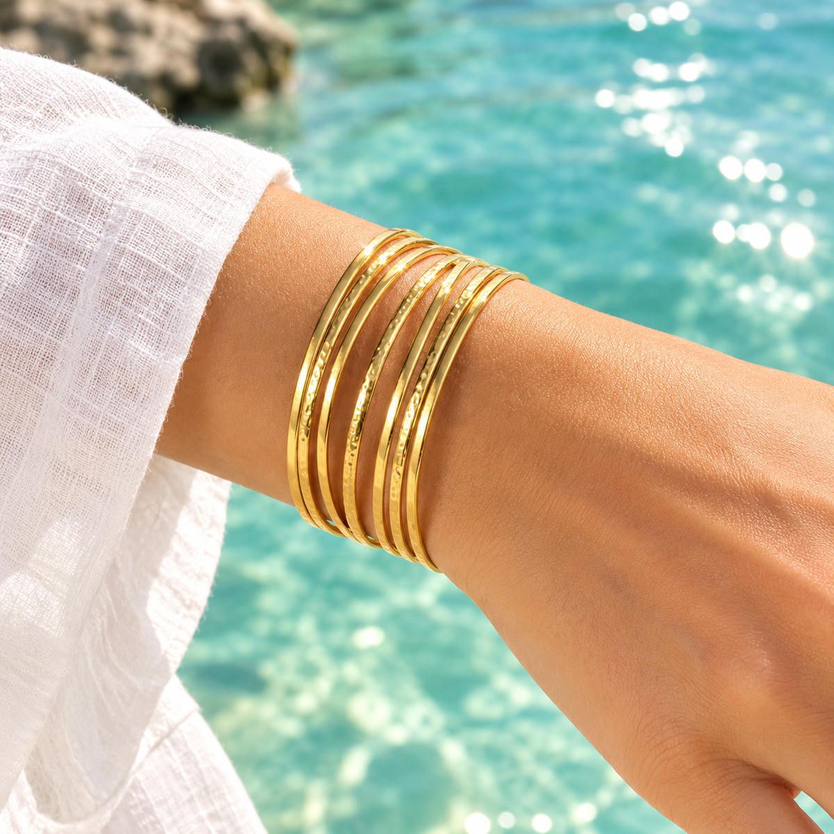 Bracelet manchette doré en acier inoxydable 316L martelé sur un poignet de femme.