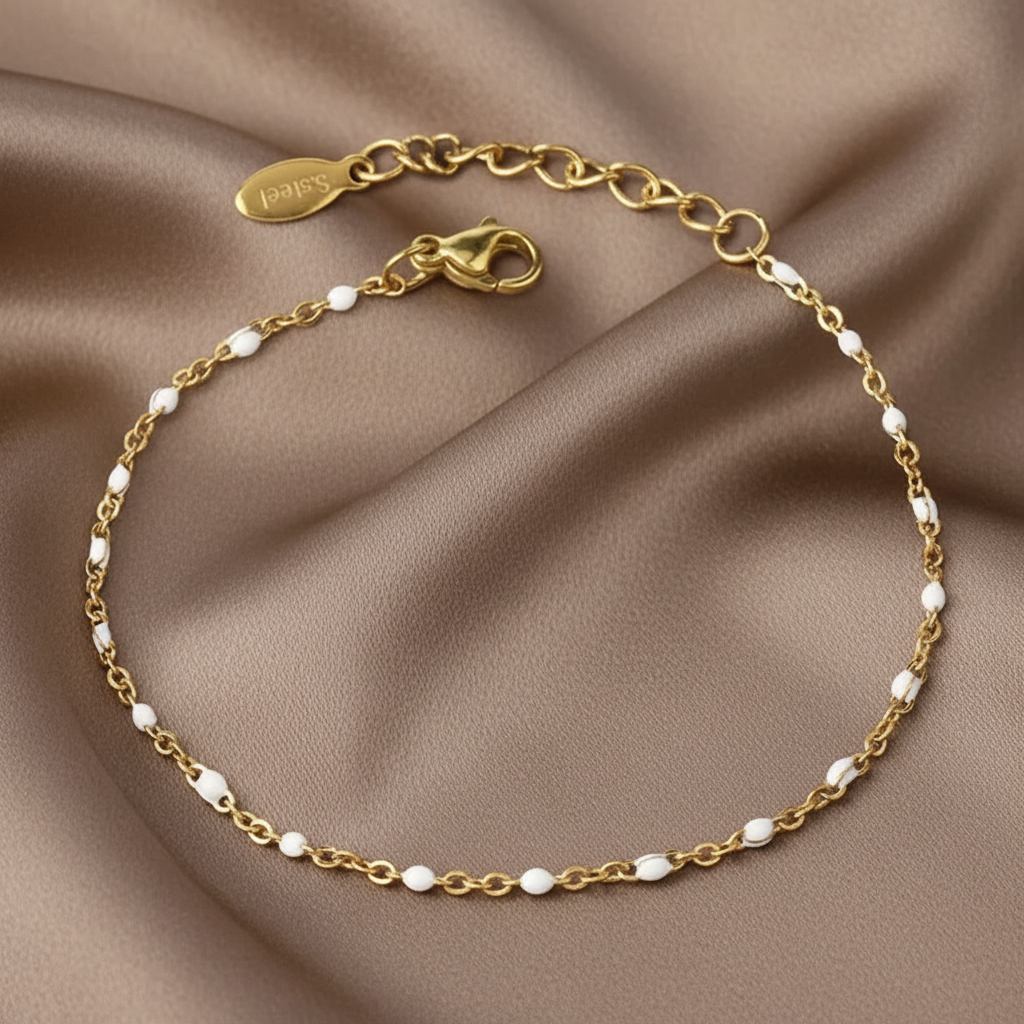 Bracelet fin doré en acier inoxydable 316L orné de perles en émail blanc.