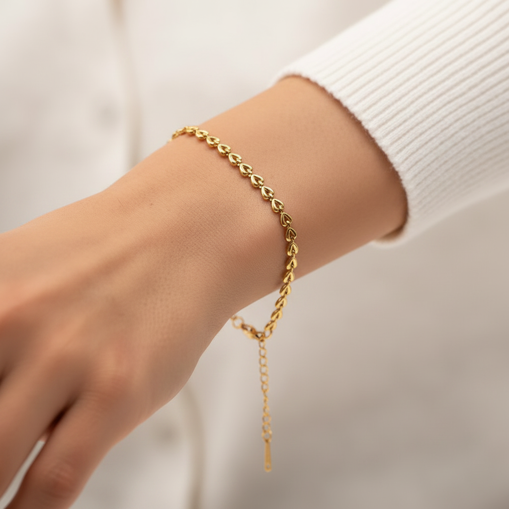 Bracelet doré en acier inoxydable 316L à chaîne de coeurs sur un poignet de femme.