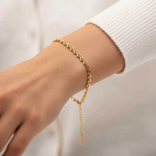 Bracelet doré en acier inoxydable 316L à chaîne de coeurs sur un poignet de femme.
