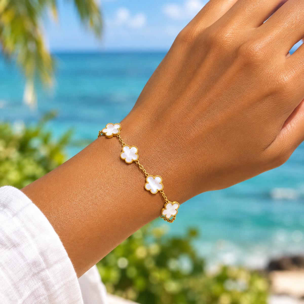 Bracelet en acier inoxydable 316L doré à chaîne fine orné de 5 fleurs en nacre naturelle blanche porté. 