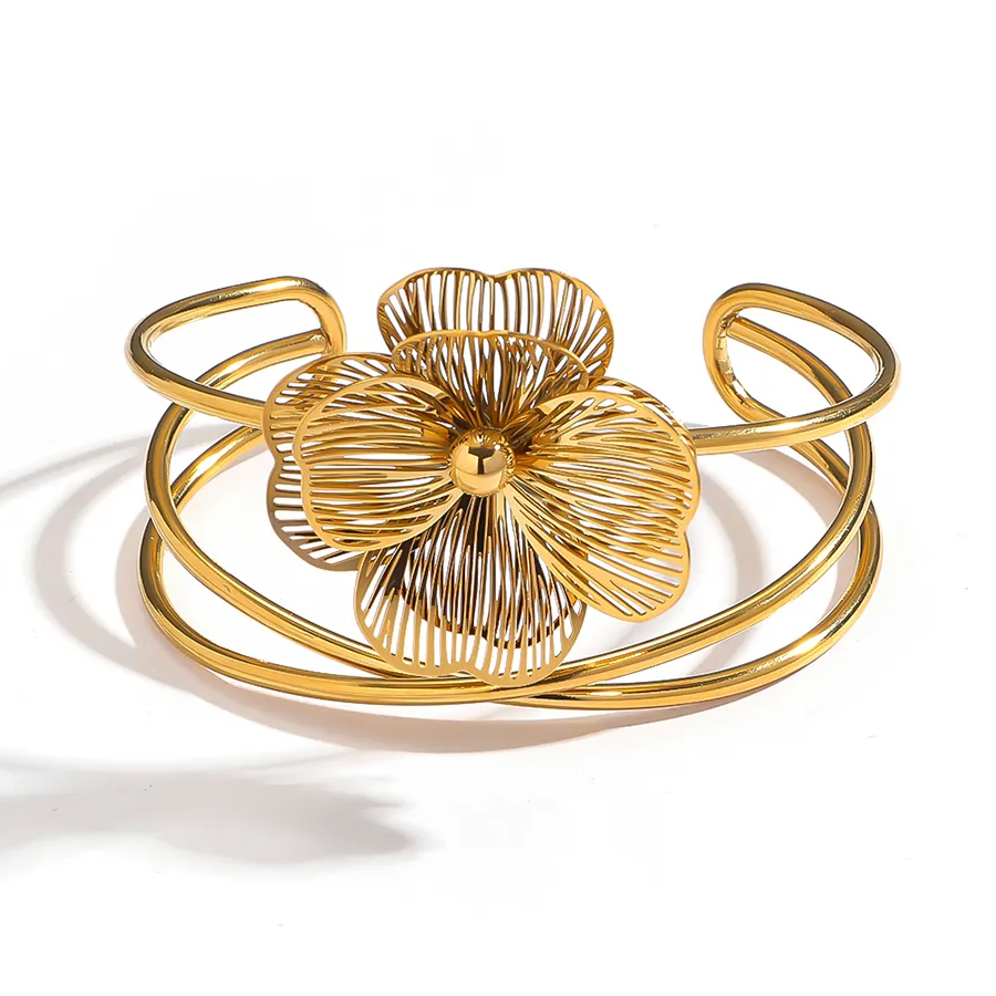 Gros plan sur un bracelet manchette en acier inoxydable 316L doré, décoré d’une grande fleur stylisée.