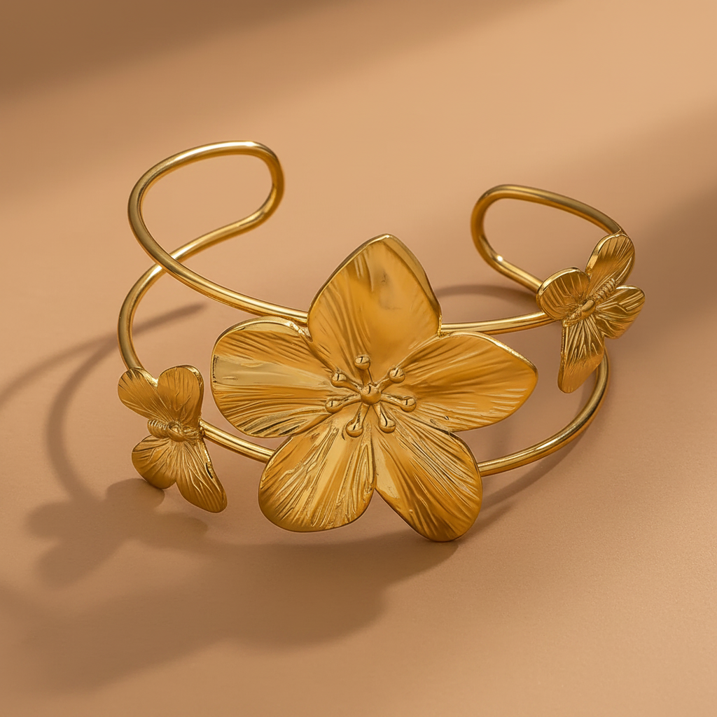 Gros plan sur un bracelet manchette en acier inoxydable 316L doré, décoré d’une grande fleur tropicale et de deux papillons.