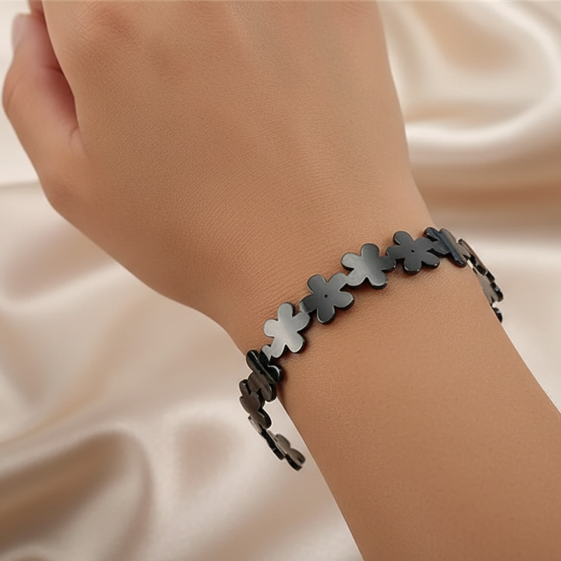 Bracelet manchette en acier inoxydable noir sur le bras d'une femme, petites fleurs décoratives, bijou bohème chic