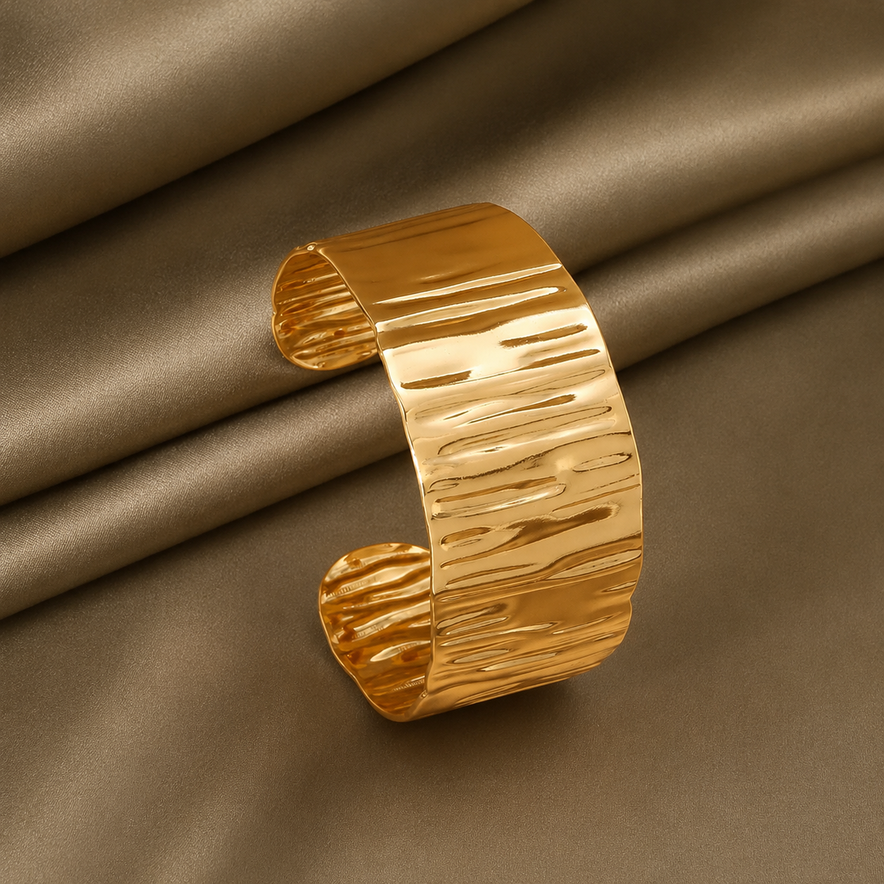 Bracelet manchette large de 3 cm en acier inoxydable doré, finition martelée et brillante.