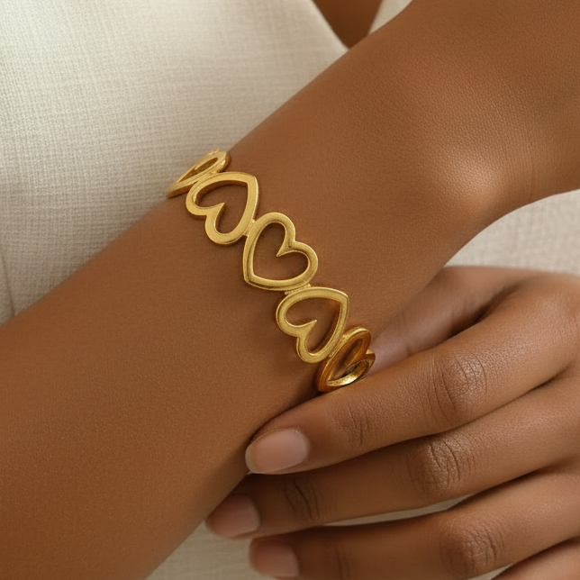 Bracelet manchette doré en acier inoxydable 316L avec coeurs ajourés porté au poignet.