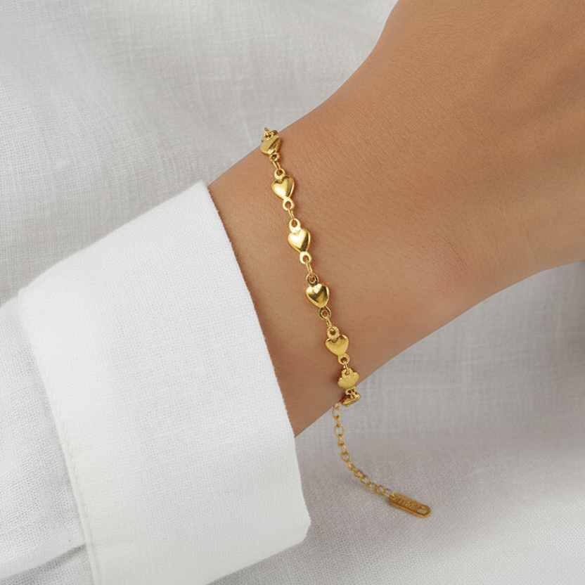 Bracelet doré en acier inoxydable 316L à chaîne de petits coeurs porté sur un poignet.