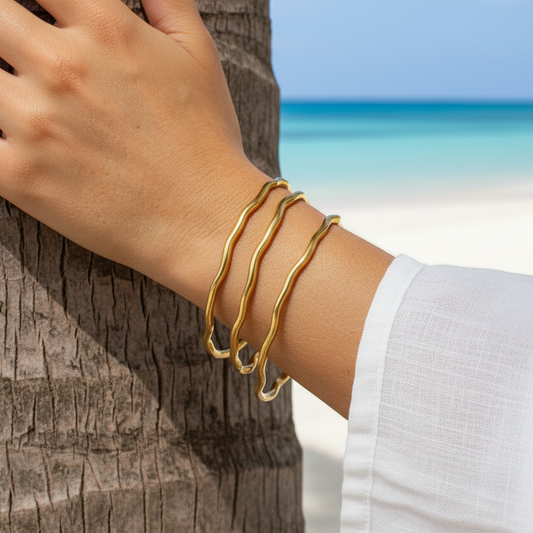 Poignet portant des bracelets jonc fins ondulés en acier inoxydable 316L doré.