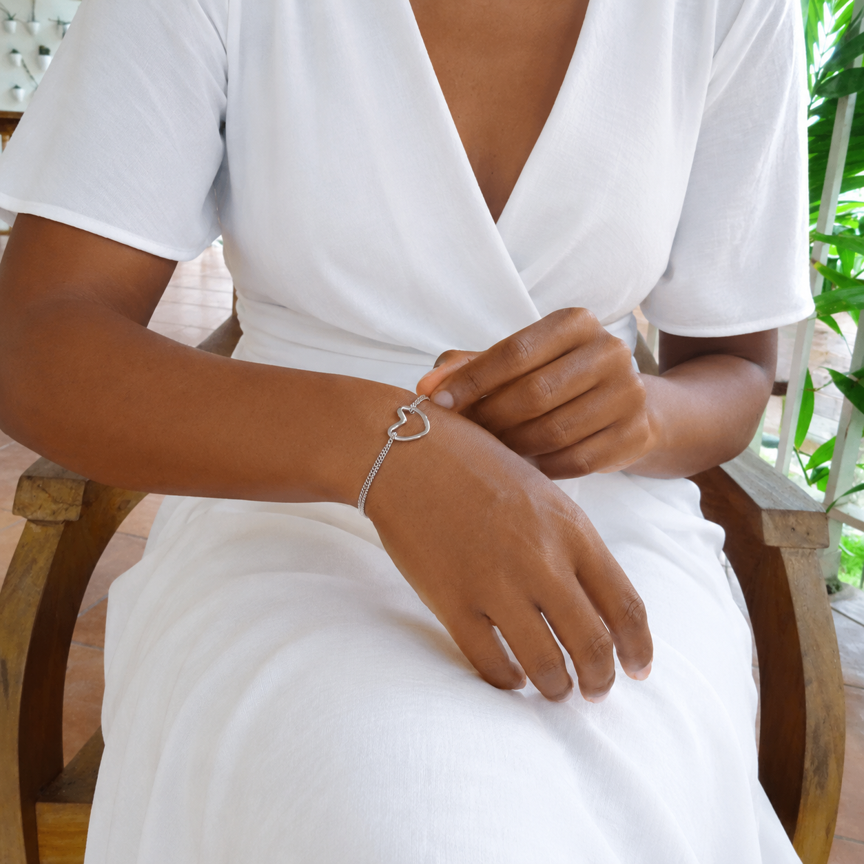 Bracelet argenté en acier inoxydable 316L à double chaîne fine maille gourmette orné d'un coeur ajouré porté sur un poignet.
