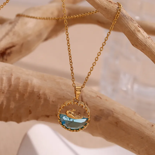 Collier doré en acier inoxydable avec fine chaîne maille forçat et pendentif rond représentant une baleine sur océan en acrylique bleu