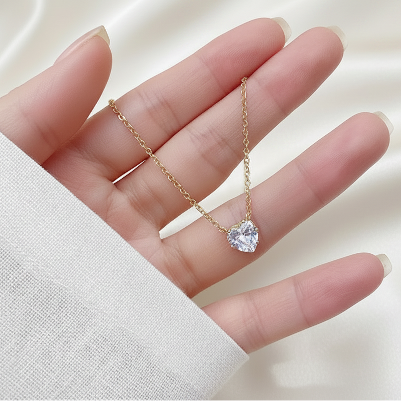 Zoom sur collier femme avec pendentif petit coeur en zirconium blanc et chaîne fine maille forçat en acier inoxydable 316L doré, bijou délicat, élégant et intemporel.