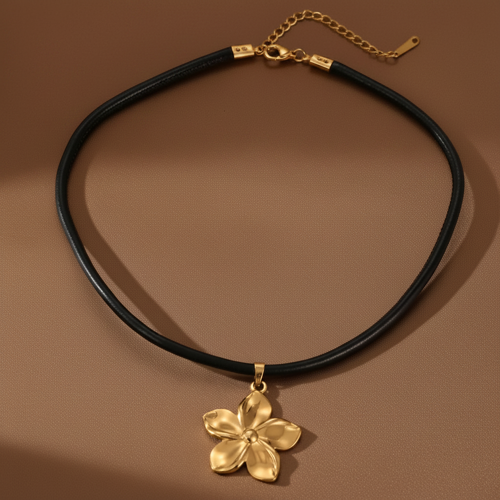 Collier avec pendentif fleur dorée en acier inoxydable et cordon en cuir noir.