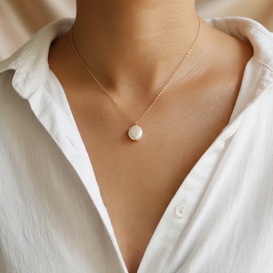 Femme portant un collier doré en acier inoxydable à fine chaîne maille forçat et grosse perle d’eau douce naturelle