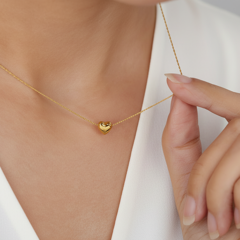 Femme portant un collier doré en acier inoxydable 316L à chaîne maille bambou ultra fine et pendentif coeur.