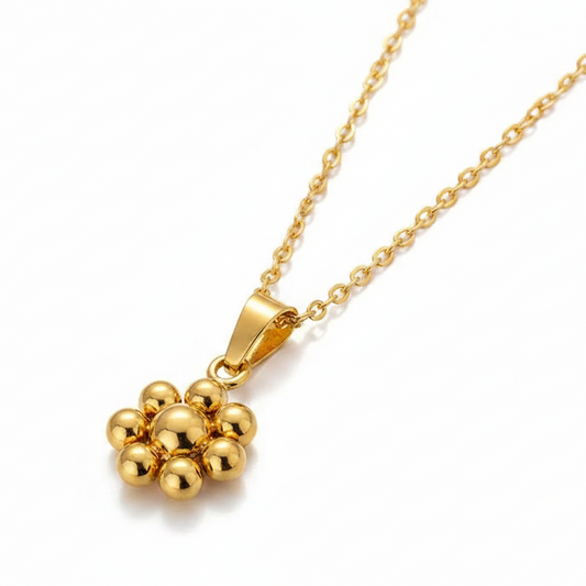 Collier doré en acier inoxydable à fine chaîne maille forçat et pendentif fleur stylisée.