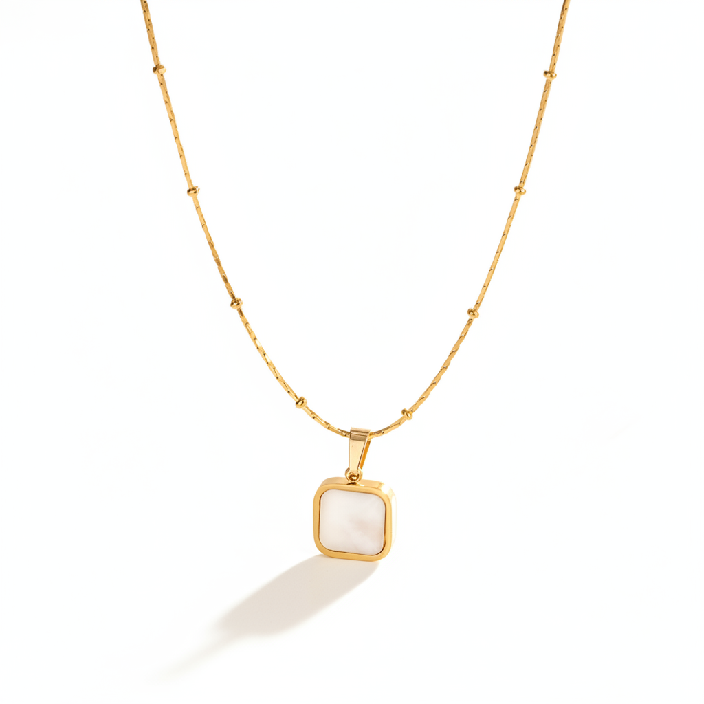 Collier doré en acier inoxydable avec pendentif carré en nacre sur fine chaîne bambou et perles.