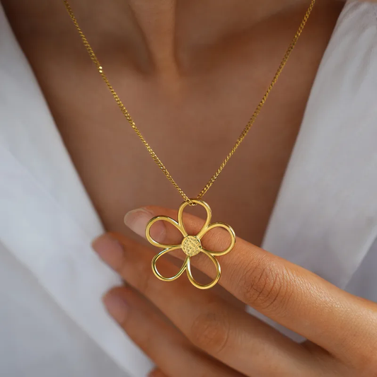Femme portant un collier doré en acier inoxydable à maille gourmette avec pendentif fleur stylisée, bijou bohème