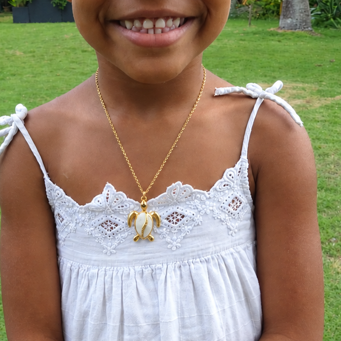 Collier doré orné d'un pendentif tortue en acier inoxydable émaillé blanc porté.