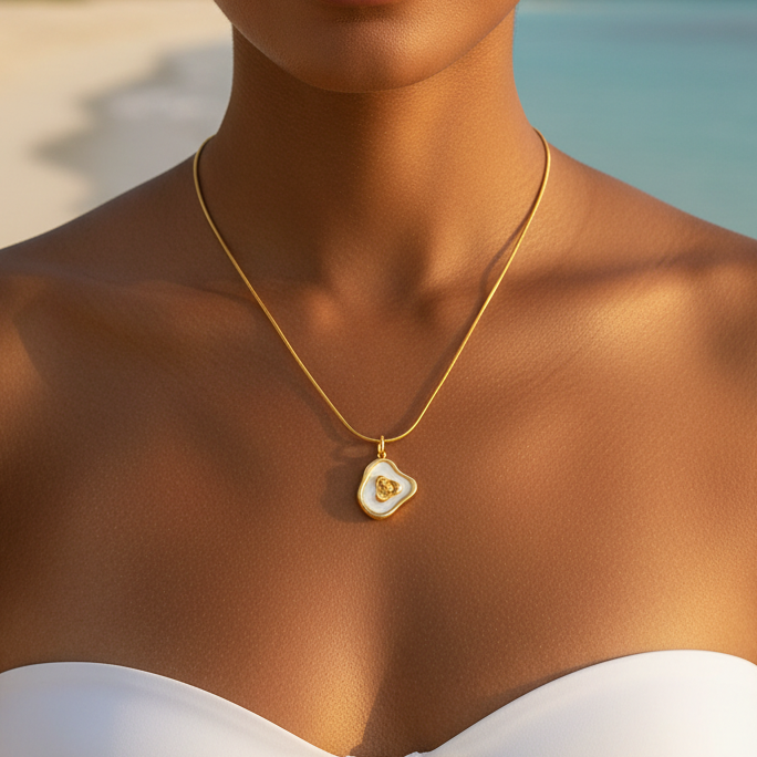 Femme portant un collier doré en acier inoxydable 316L à fine chaîne maille serpent orné d'un pendentif en nacre et coeur doré.