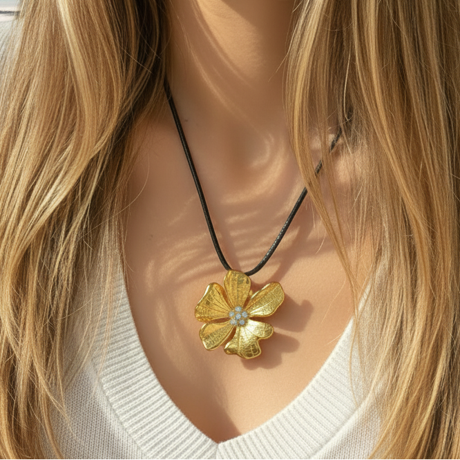 Femme portant un collier fleur doré en acier inoxydable 316L orné d'un cœur avec six zircons blancs, cordon cuir noir.