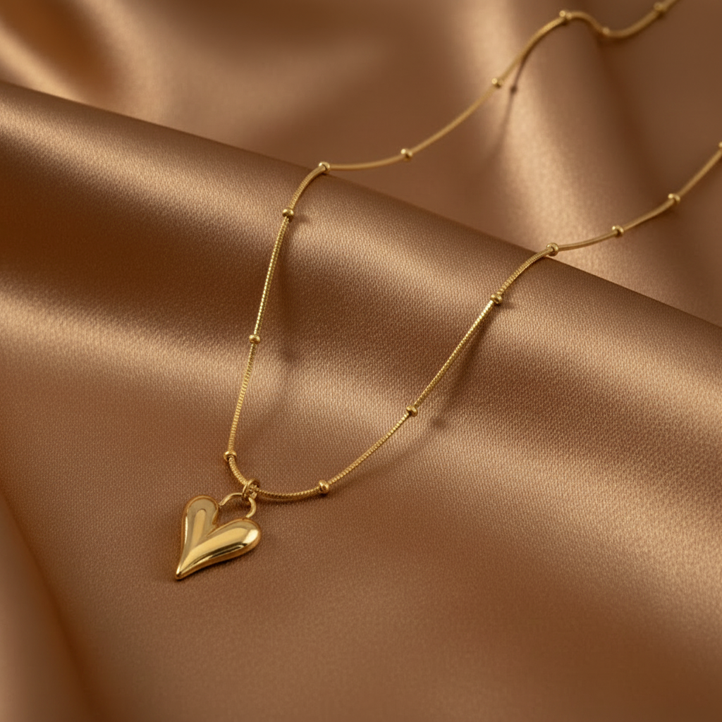Collier doré en acier inoxydable 316L à fine chaîne serpent perlée et pendentif coeur stylé.