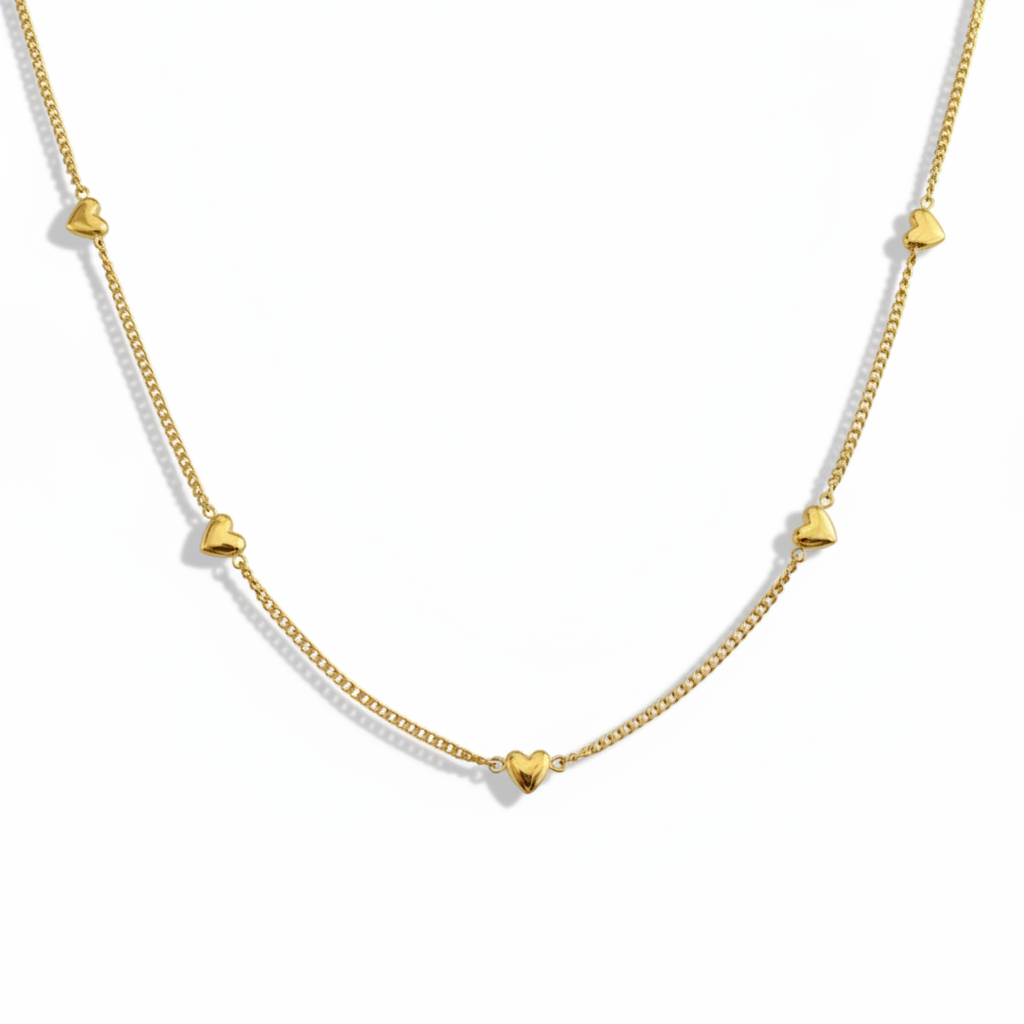 Gros plan sur un collier doré en acier inoxydable 316L à fine maille gourmette orné de neuf petits cœurs.