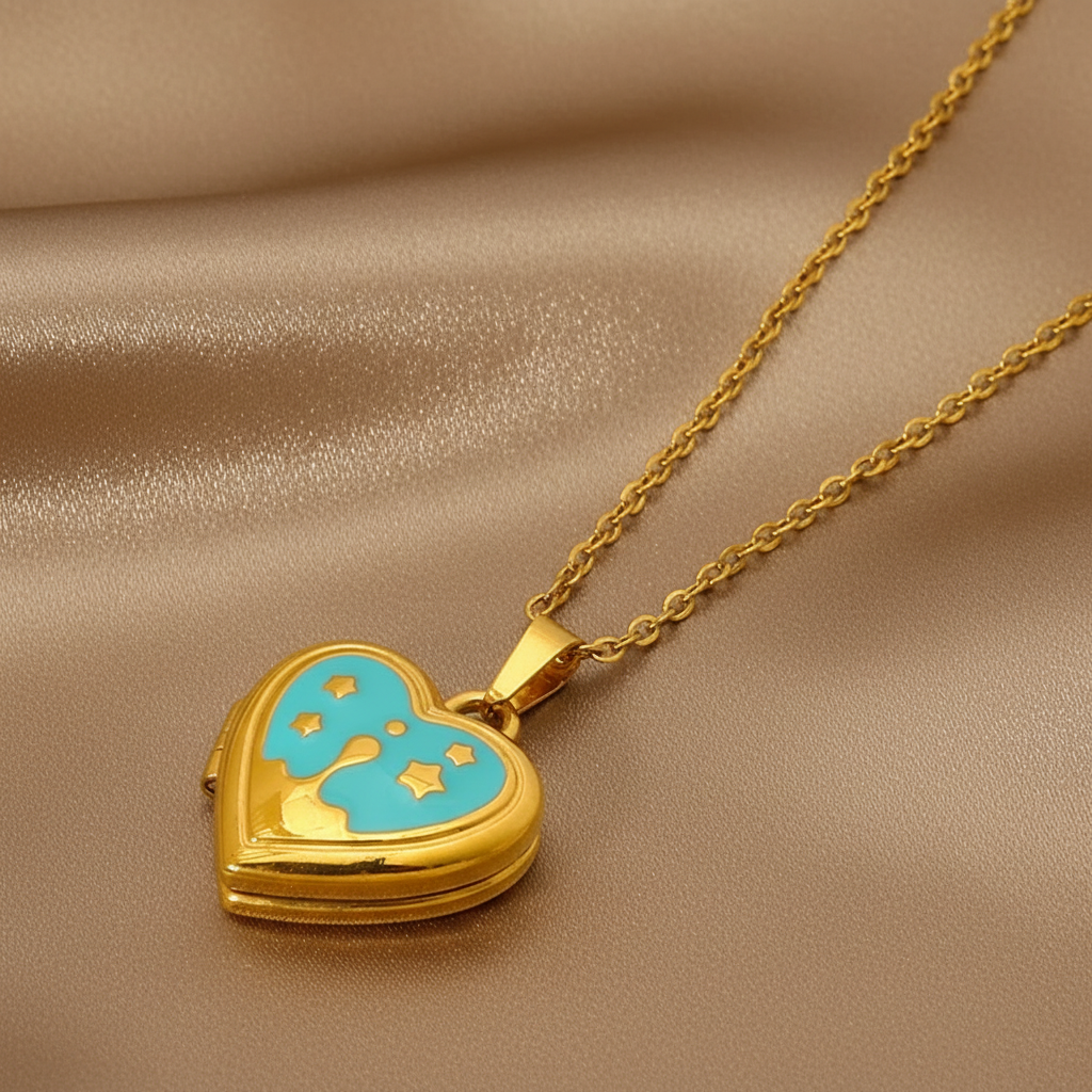 Gros plan sur un collier doré en acier inoxydable 316L à maille forçat fine avec pendentif cœur ouvert en émail bleu.