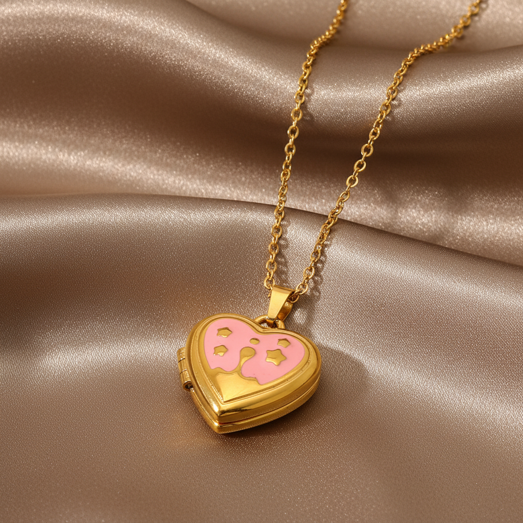 Gros plan sur un collier doré en acier inoxydable 316L à maille forçat fine avec pendentif cœur ouvert en émail rose.