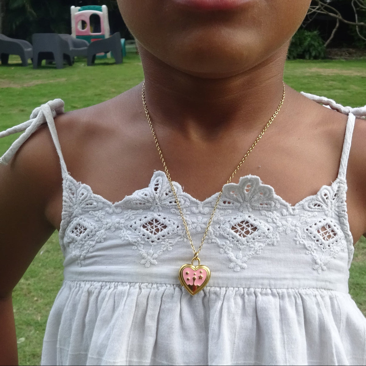 Collier doré en acier inoxydable 316L à maille forçat fine avec pendentif cœur ouvert en émail rose porté.
