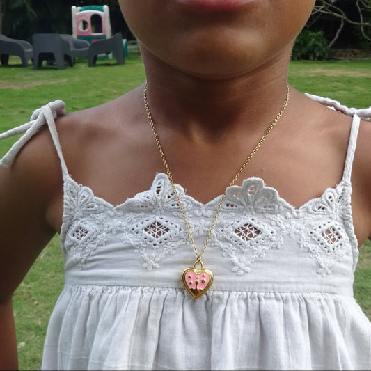 Collier doré en acier inoxydable 316L à maille forçat fine avec pendentif cœur ouvert en émail rose porté.
