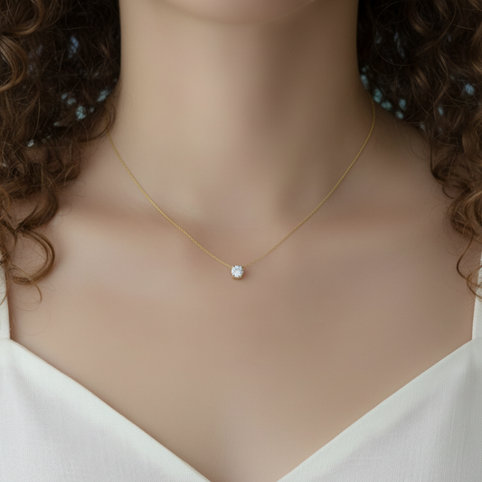 Femme portant un collier en acier inoxydable 316L doré à chaîne ultra fine maille bambou et pendentif petit rond en zirconium blanc, bijou délicat, élégant et intemporel