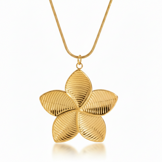 Gros plan sur collier doré en acier inoxydable à chaîne maille serpent orné d'un pendentif grande fleur tropicale de tiaré.