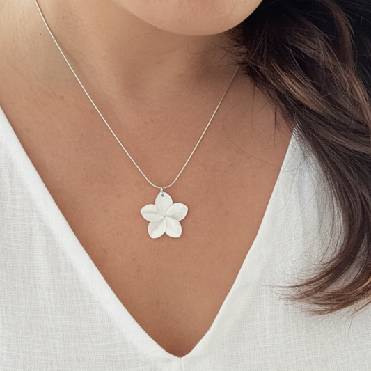 Femme portant un collier argenté en acier inoxydable à maille serpent et pendentif fleur en nacre, bijou bohème proposé par Swann Bijoux Guadeloupe