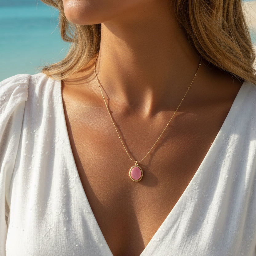 Femme portant un collier doré en acier inoxydable à fine chaîne maille corde et perles orné d'un pendentif en rhodochrosite naturelle.
