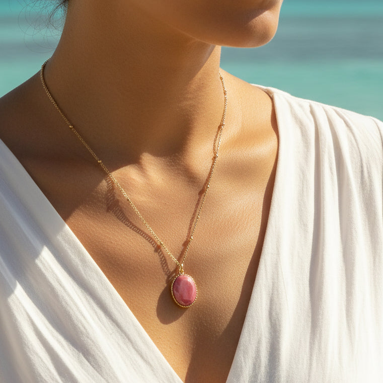 Femme portant un collier doré en acier inoxydable à maille gourmette avec des perles dorées et un pendentif en rhodochrosite naturelle taillé, style bohème
