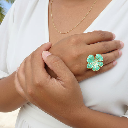 Femme portant une bague dorée ajustable en acier inoxydable, ornée d’une grande fleur verte en émail. 