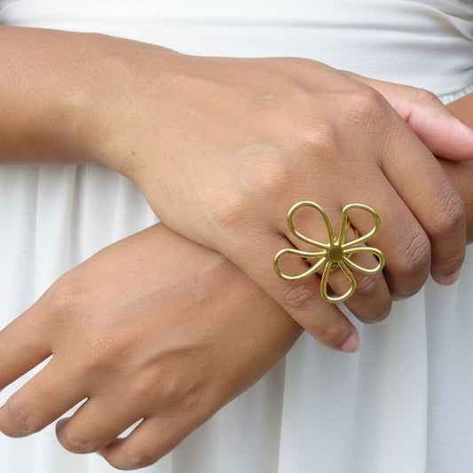 Femme portant une bague dorée ajustable en acier inoxydable, ornée d’une grande fleur stylisée et ajourée.