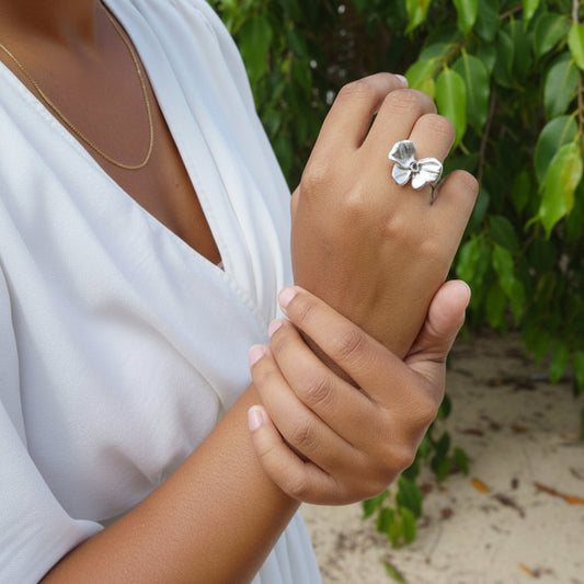 Femme portant une bague argentée ajustable en acier inoxydable 316L avec fleur papillon.