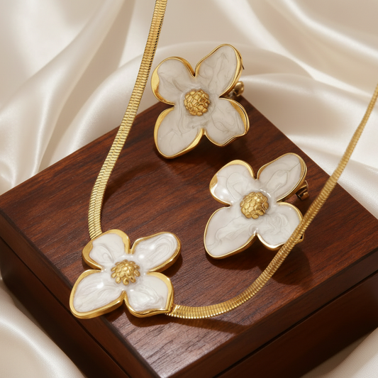 Zoom sur une parure à grande fleur émaillée blanc en acier inoxydable doré composée d'un collier à maille serpent et boucles d'oreilles, bijou bohème et tendance