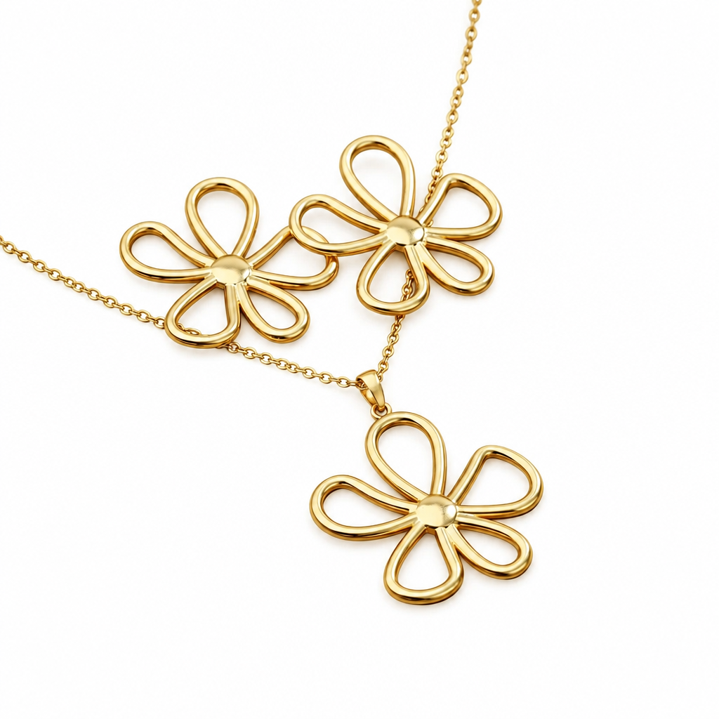 Parure grande fleur ajourée comprenant un collier et des boucles d'oreilles en acier inoxydable doré sur fond banc.