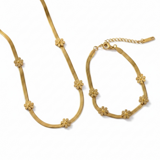 Parure comprenant un collier et un bracelet en acier inoxydable doré à maille serpent large de 3 mm et ornée de 5 petites fleurs.