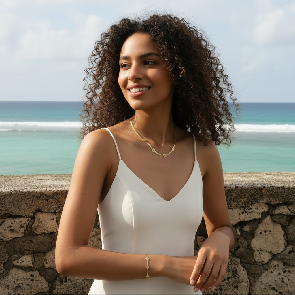 Femme portant une parure collier et bracelet doré en acier inoxydable à maille serpent large de 3 mm orné de 5 petites fleurs, bijou tendance